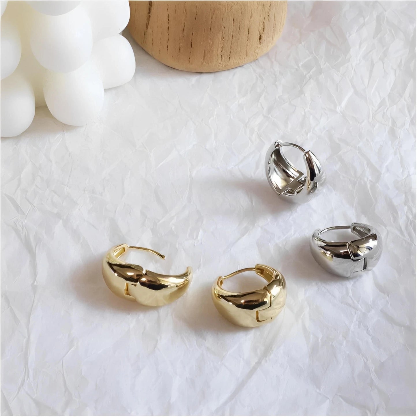 Gold and silver chunky hoop earrings on crumpled white background