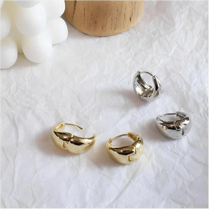 Gold and silver chunky hoop earrings on crumpled white background