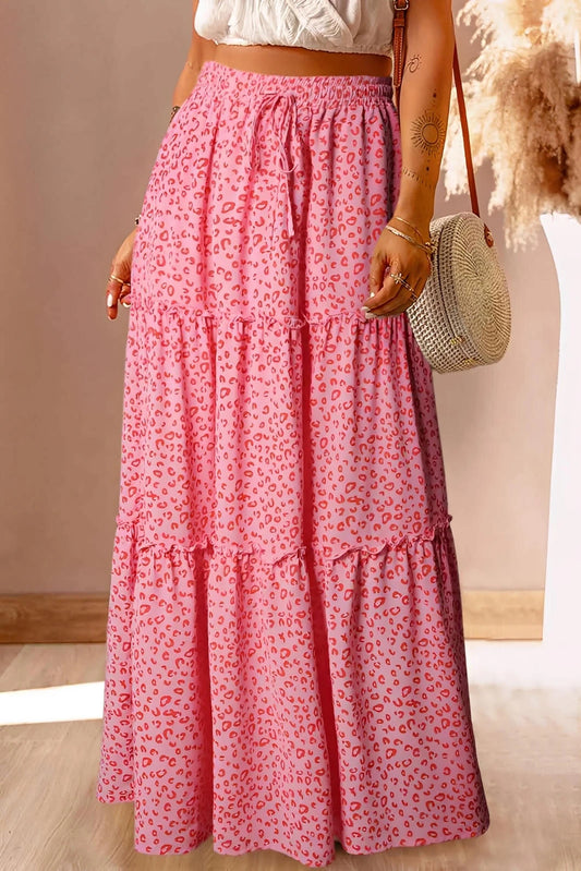 Woman wearing a pink leopard print maxi skirt with tiered layers and a woven round bag