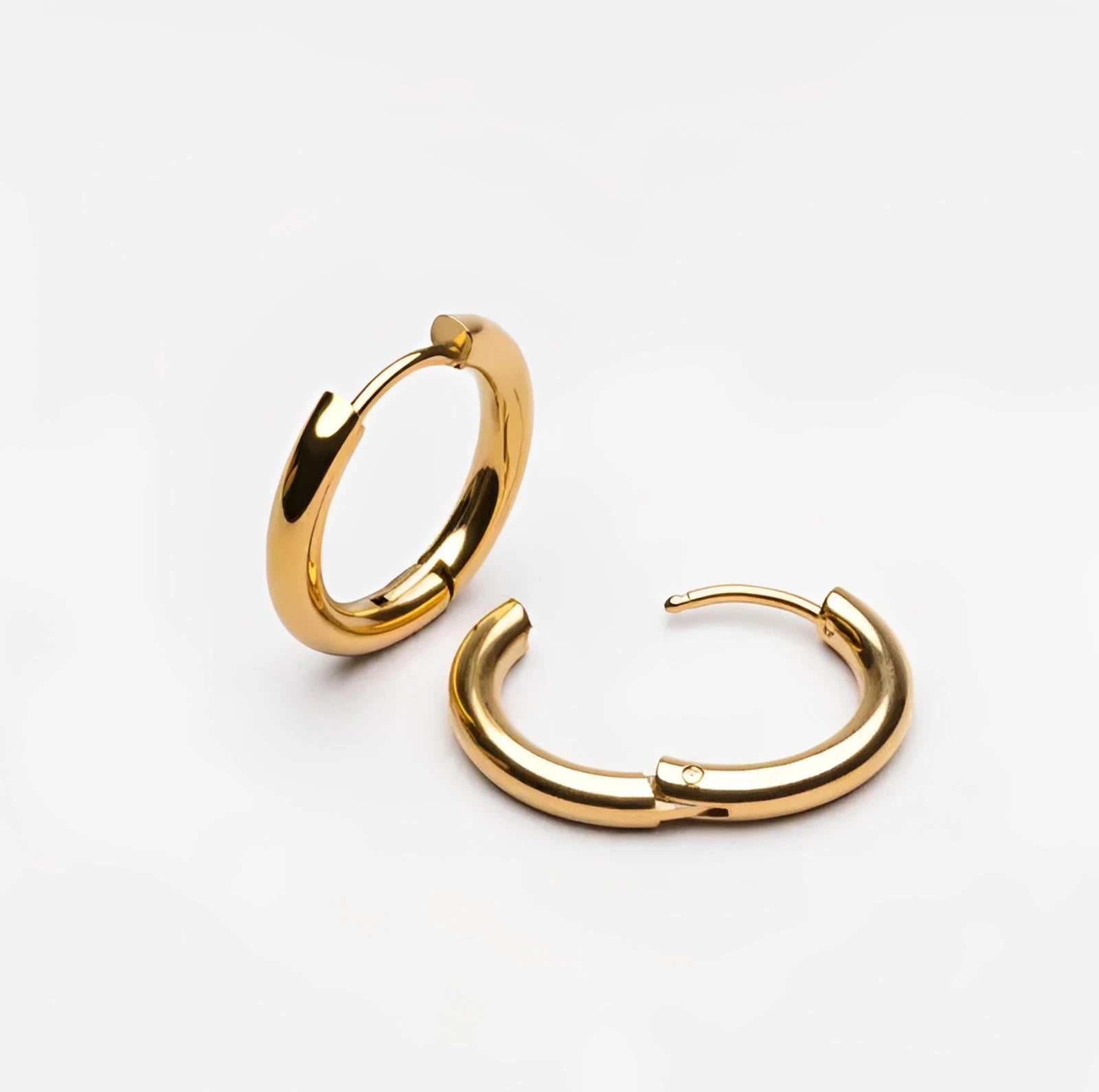 Pair of gold hoop earrings on white background, minimalist jewelry